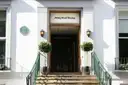 The white front of Abbey Road Studios in London, with steps, green railings and two lamps by the door