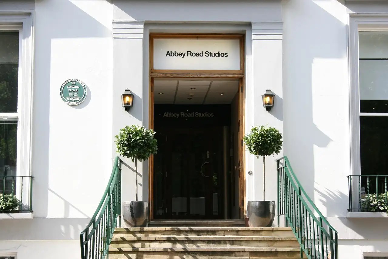 The white front of Abbey Road Studios in London, with steps, green railings and two lamps by the door