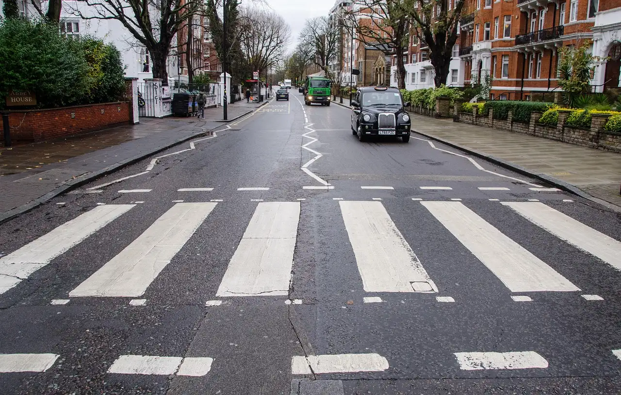 Zebra crossing on Abbey Road in London with a black cab further up the street