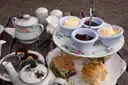 A tiered stand with scones, clotted cream and jam next to a china teapot