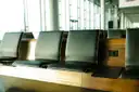 Dark leather seats in a bright airport hall with tall windows