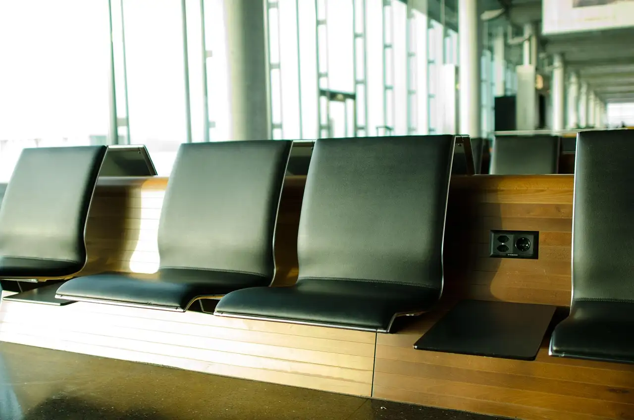 Dark leather seats in a bright airport hall with tall windows