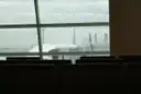 Seats facing a big airport window, with a plane parked outside
