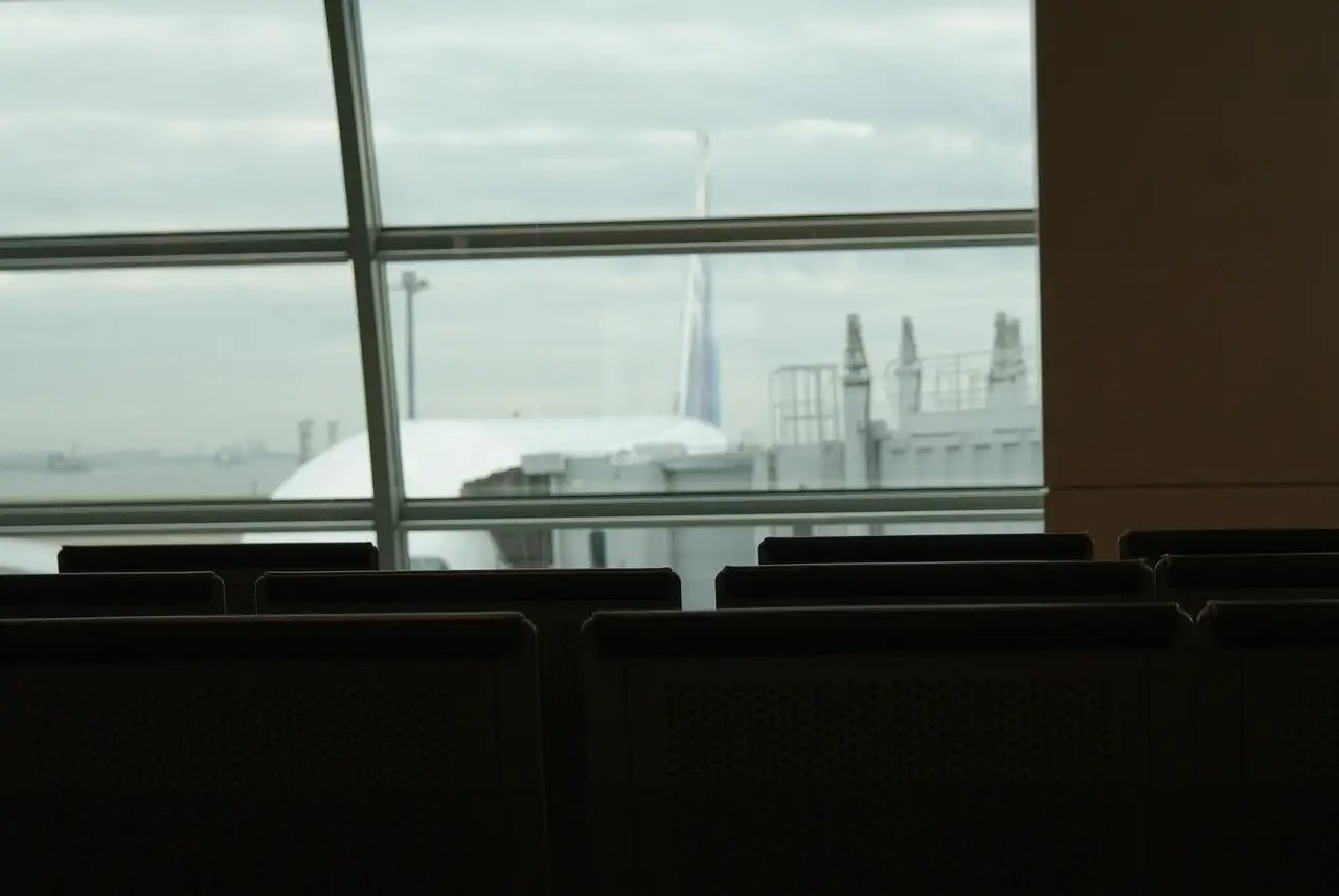 Seats facing a big airport window, with a plane parked outside