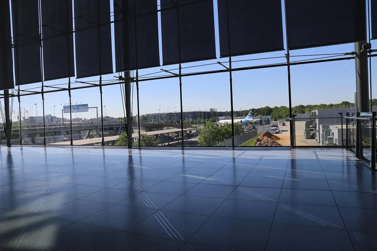 An empty airport terminal in front of a tall glass wall overlooking the airfield