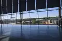 An empty airport terminal in front of a tall glass wall overlooking the airfield