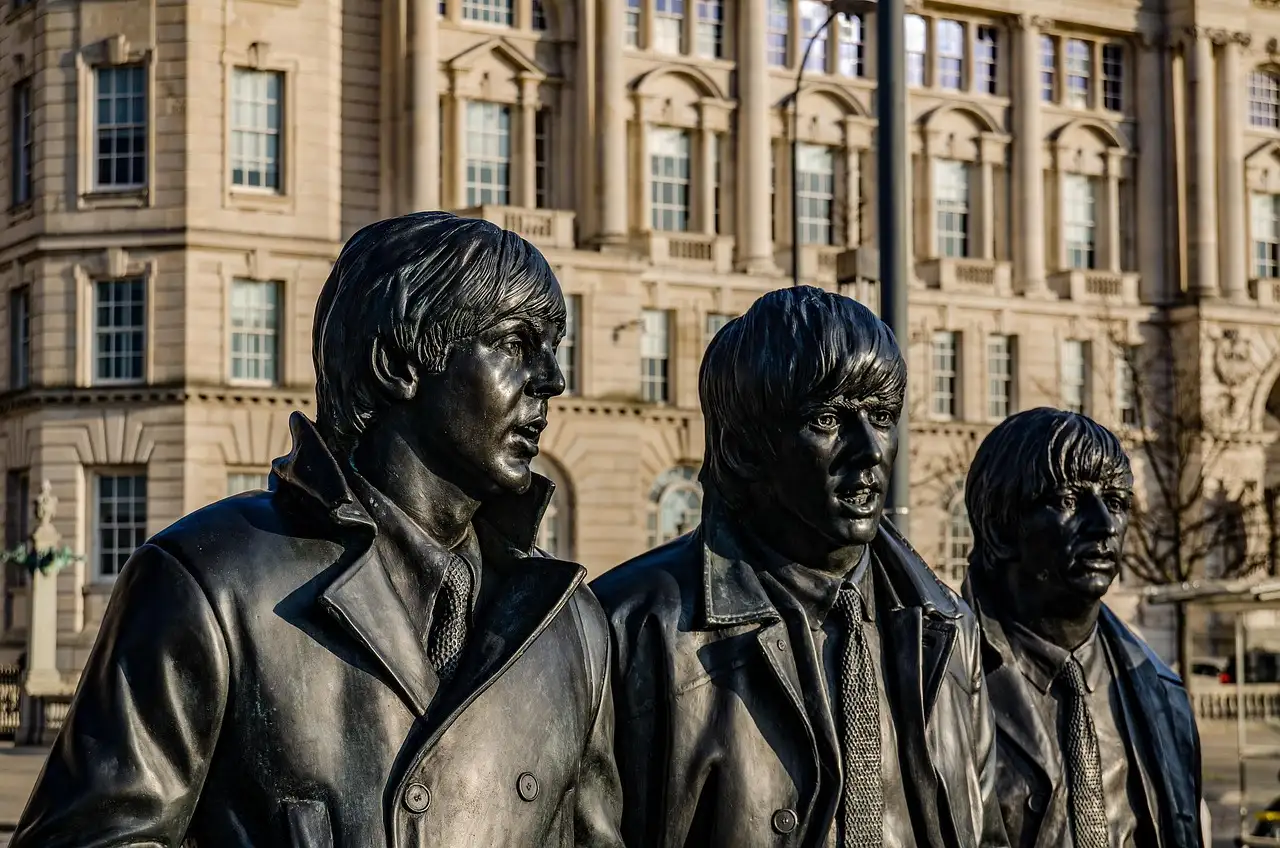 Bronze faces of the Beatles statue with historic buildings behind