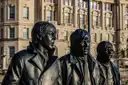 Bronze faces of the Beatles statue with historic buildings behind
