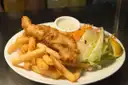 Battered fish and chips with tartare sauce and a lemon wedge on a white plate