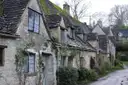 Stone cottages with climbing plants along a street in Bibury