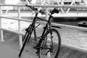 Bicycle leaning on a riverside railing in black and white