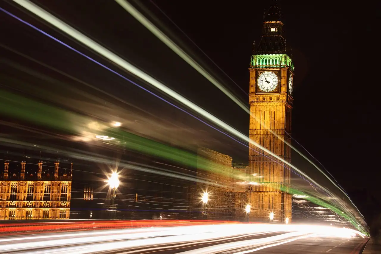 Big Ben lit up at night with light trails from passing traffic