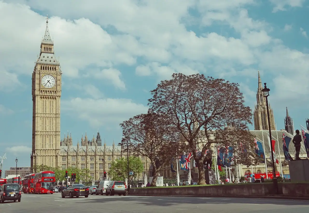 Big Ben over Parliament Square, with red double-decker buses on the road below
