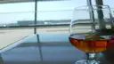 A glass of brandy on a table by a window overlooking an airport