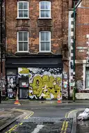 An old brick terrace house with painted shutters on a street corner off Brick Lane, East London