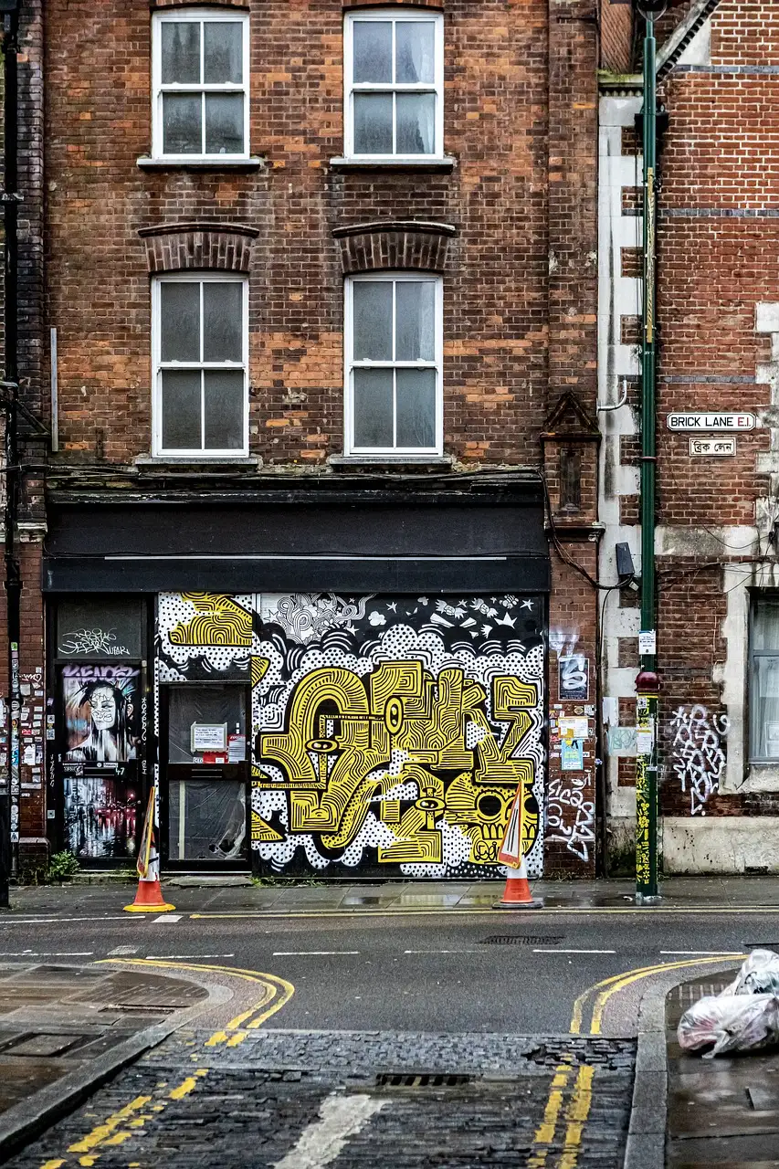 An old brick terrace house with painted shutters on a street corner off Brick Lane, East London