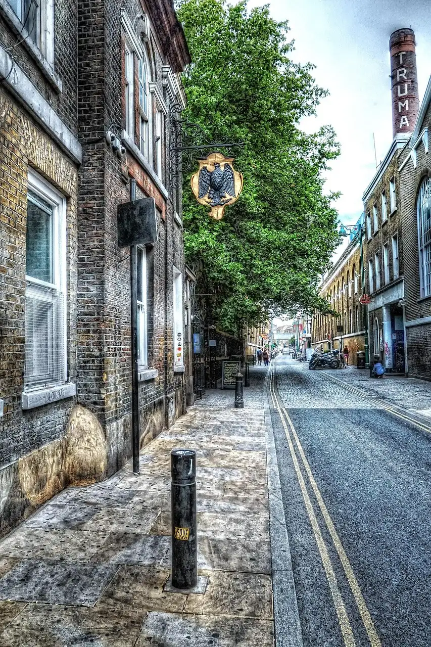 A quiet Victorian street of brick buildings off Brick Lane, with an old brewery chimney behind