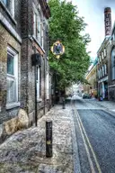 A quiet Victorian street of brick buildings off Brick Lane, with an old brewery chimney behind
