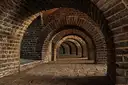 Brick vaulted arches receding into a dim underground passage