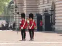 Two guardsmen in red tunics and bearskin hats beside sentry boxes at Buckingham Palace
