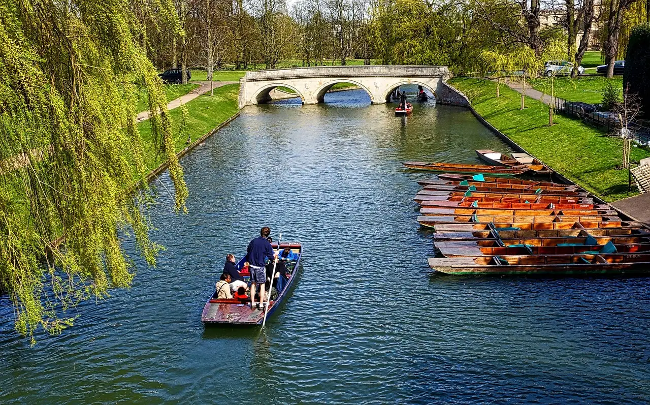 Punts on the River Cam under willow trees with a stone bridge behind