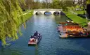 Punts on the River Cam under willow trees with a stone bridge behind