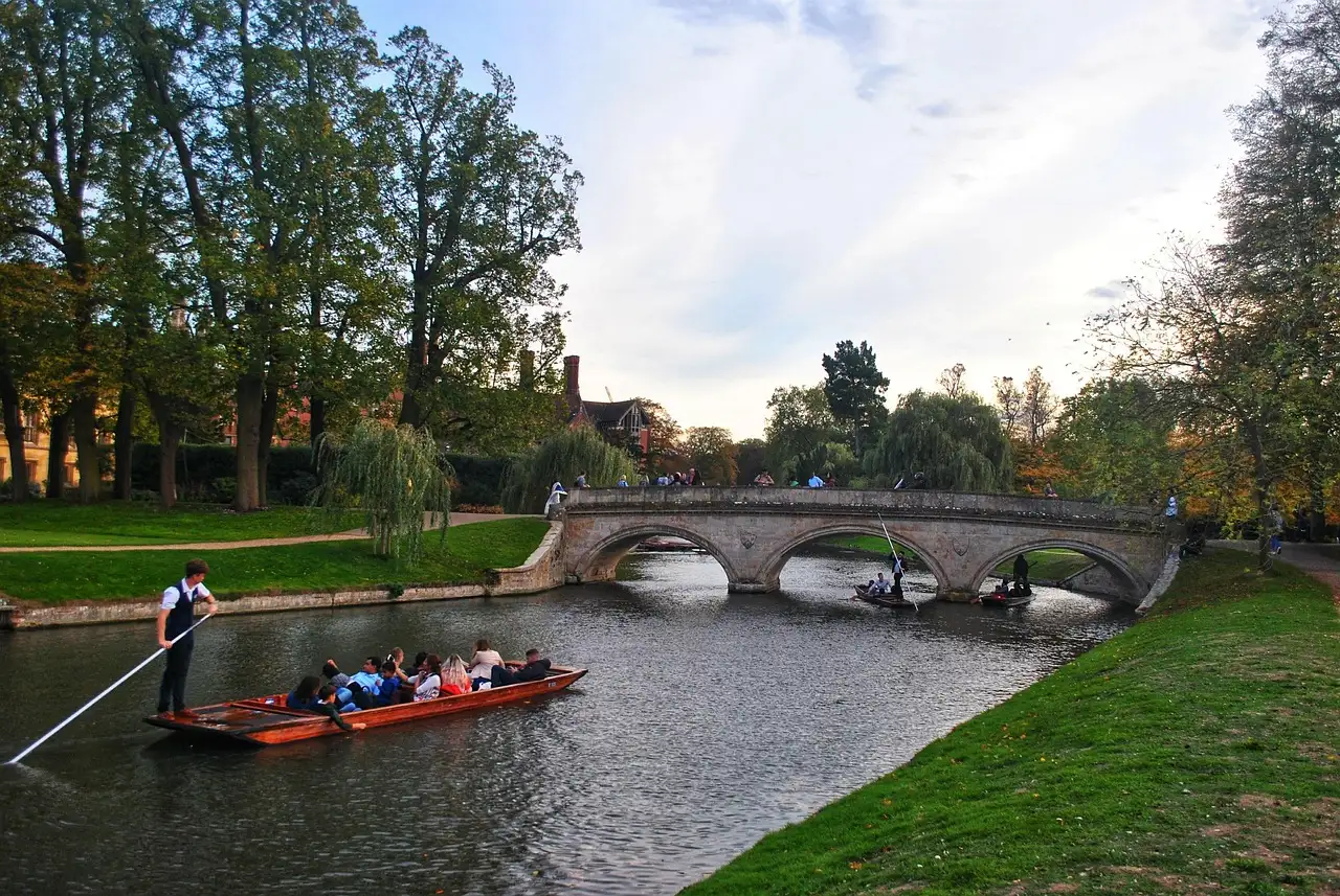 Punt being poled along the River Cam towards a stone bridge