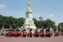 Guards in red tunics and bearskins marching past the Victoria Memorial
