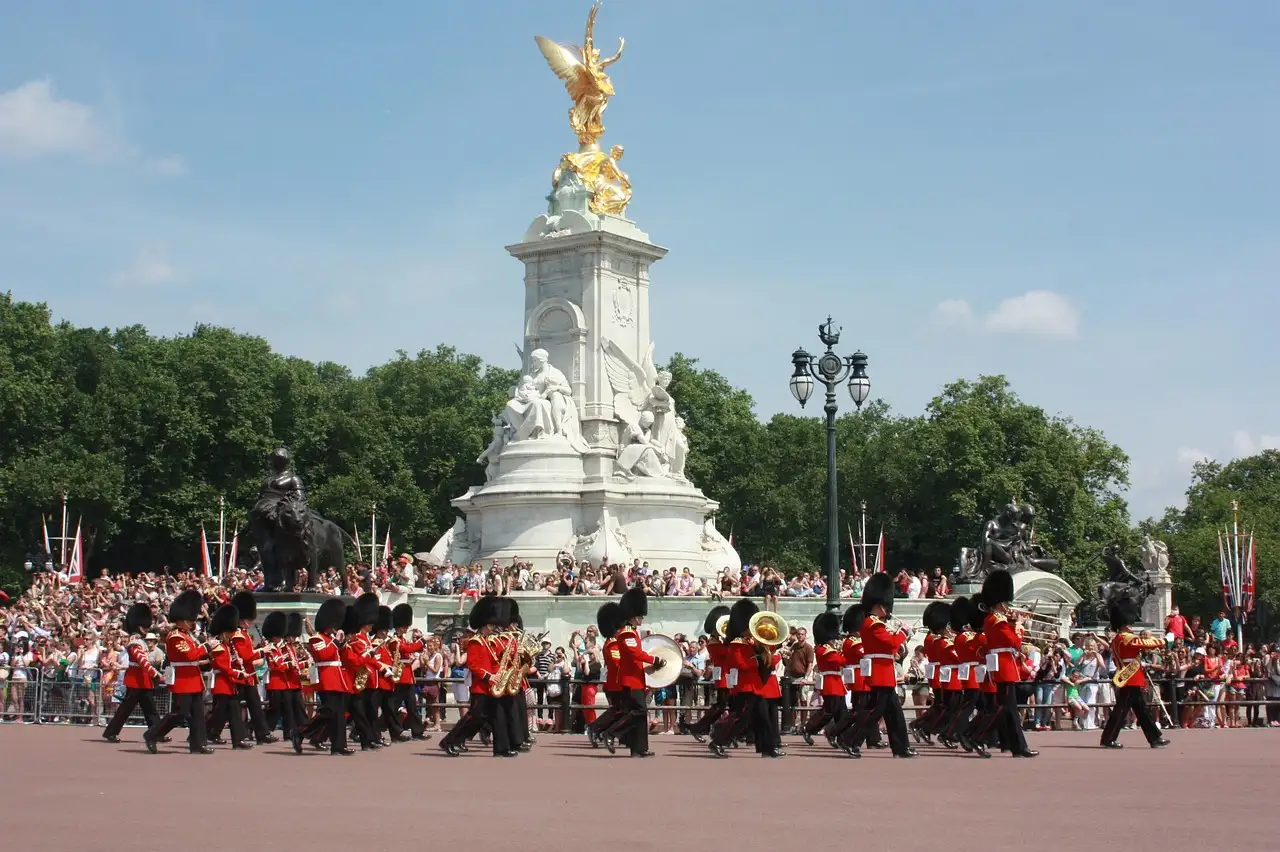 Guards in red tunics and bearskins marching past the Victoria Memorial