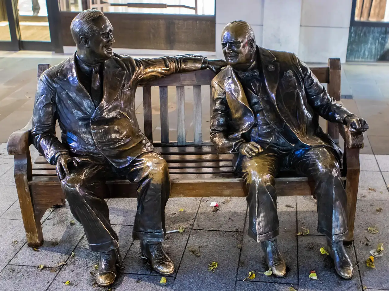 Bronze statues of Churchill and Roosevelt sitting together on a bench