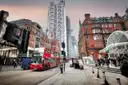 Red double-decker buses on a City of London street, with glass towers behind
