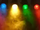 Blue, yellow, green and red stage lights shining through haze