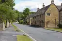 Cotswold village street lined with yellow limestone houses