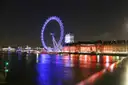 The London Eye and County Hall lit up at night, reflected in the Thames