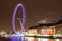 County Hall lit up at night beside the glowing London Eye on the Thames
