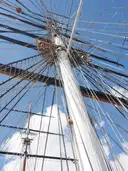 The masts and rope rigging of the Cutty Sark against a blue sky