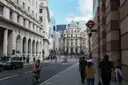 A cyclist riding through the City of London past grand stone buildings