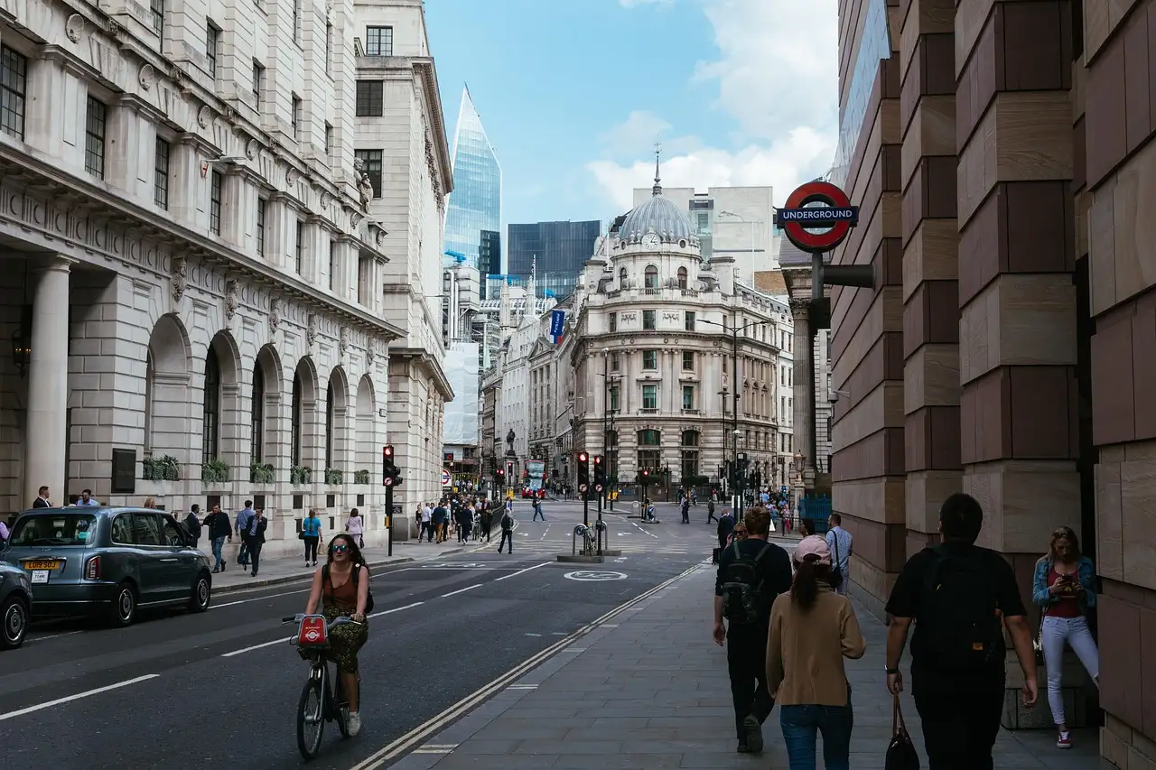 A cyclist riding through the City of London past grand stone buildings