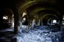 A dark vaulted stone cellar with crumbling pillars