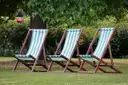 Three striped deckchairs on the grass in a London park