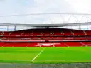 Red stands inside the Emirates Stadium, seen from the edge of the pitch