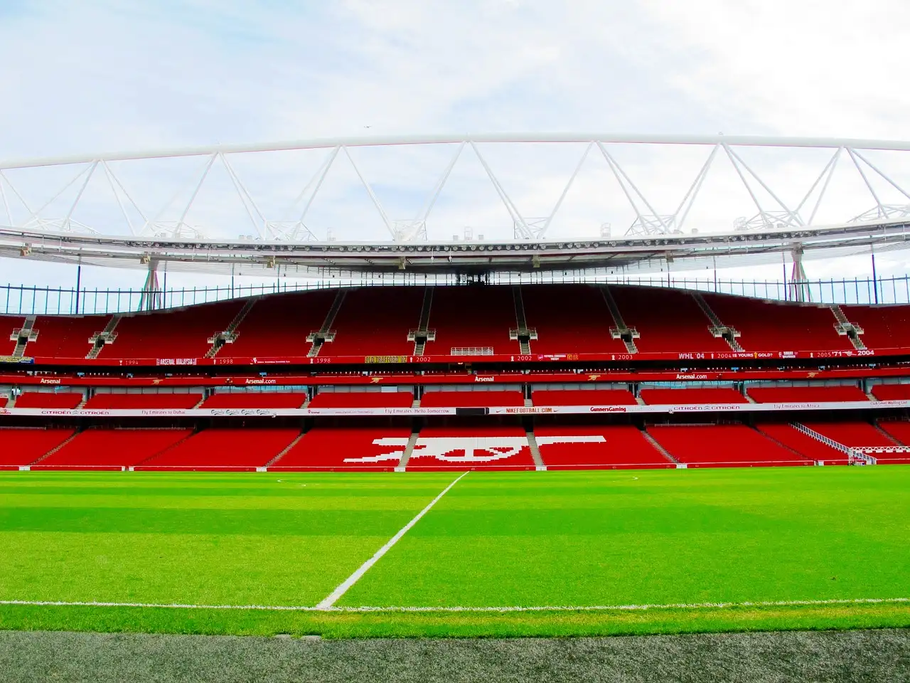 Red stands inside the Emirates Stadium, seen from the edge of the pitch