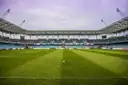 An empty football stadium from pitch level, with a ball on the grass