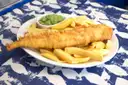 A plate of battered fish and chips with mushy peas