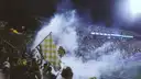 Football fans waving flags in the stands with smoke over the crowd