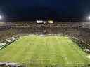 A night football match seen from high in the stands, crowds around the lit pitch