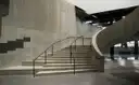 A wide concrete staircase with a curved handrail rising through the bare industrial hall of a modern art museum
