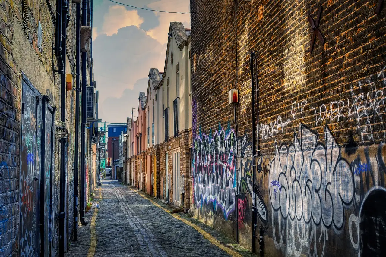 A narrow brick alley in London with graffiti on the walls