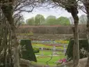 Spring flower beds in a walled garden at Hampton Court Palace, seen through an arbour