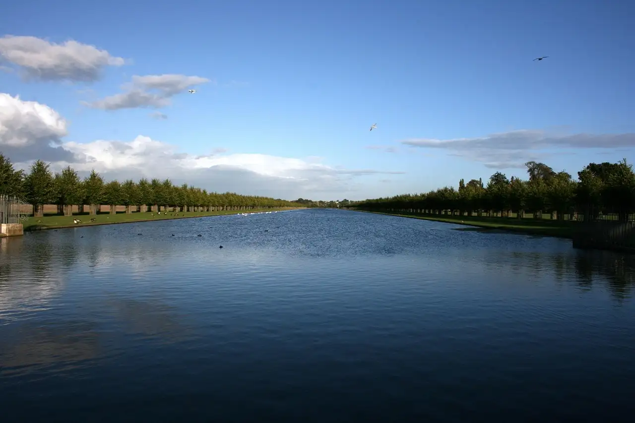 The tree-lined Long Water canal at Hampton Court under a blue sky
